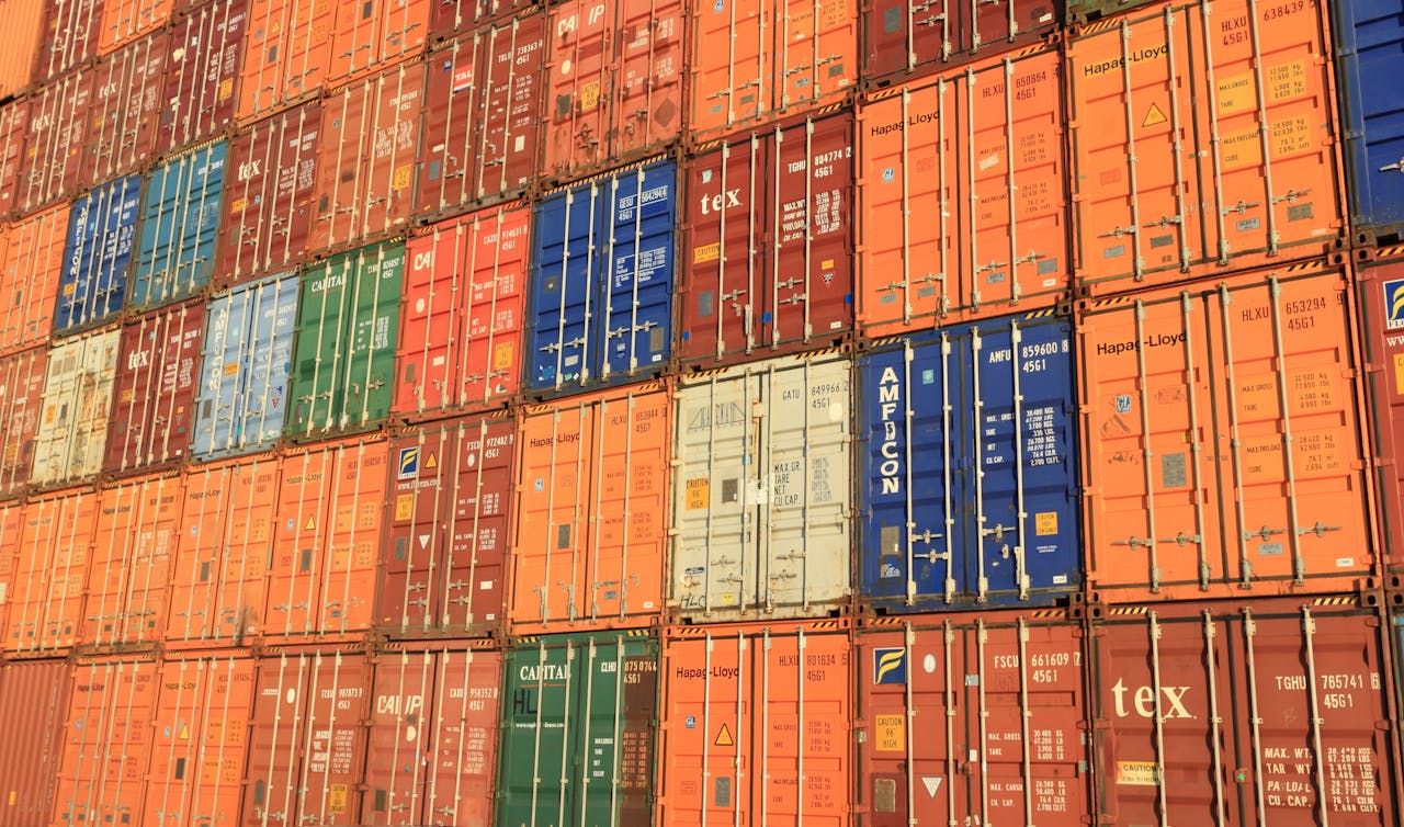 heros-img Colorful shipping containers stacked in a harbor, symbolizing global trade.